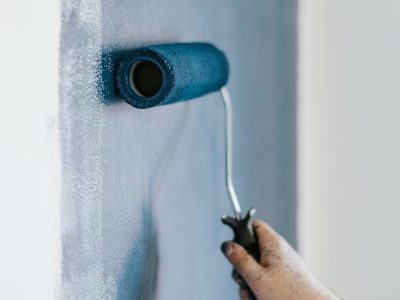 A closeup shot of a female using paint rollers with the color blue